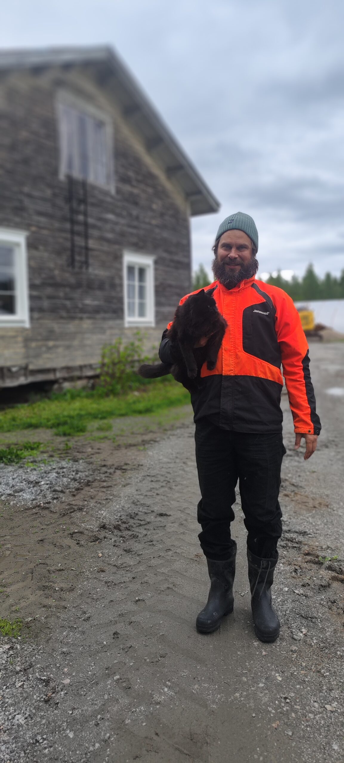 Viljelijä Timo Junnikkala kissan kanssa pihamaalla
